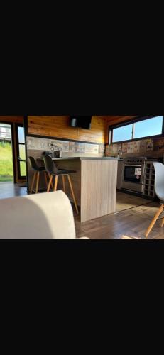 a kitchen with a counter and a table and chairs at Cabañas Luz de Luna, Playa Curanipe in Curanipe
