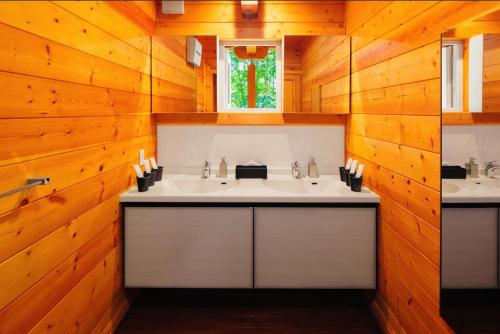 two sinks in a bathroom with wooden walls at La Chalet by Jade Group in Nagano