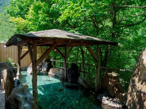 a wooden gazebo with a pool of water at 層雲閣 in Kamikawa