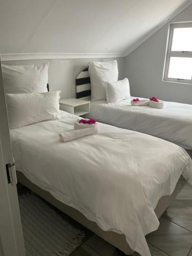 two beds with white sheets and pink flowers on them at Riverside Recreation Lodge in Katima Mulilo