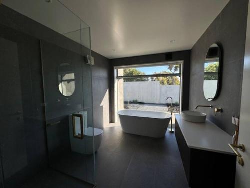 a bathroom with a tub and a large window at Location and luxury in Timaru in Timaru