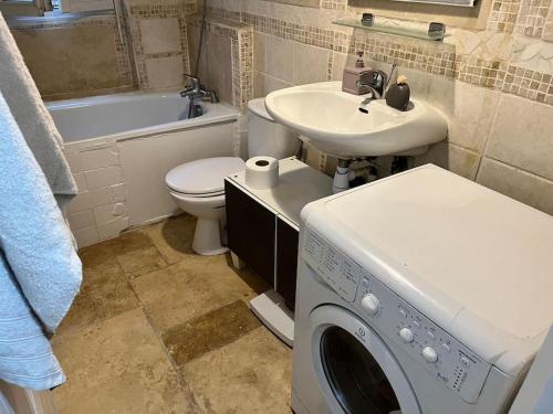 une salle de bain avec une machine à laver et un lavabo dans l'établissement Joli deux pièces porte de Paris, à Saint-Denis