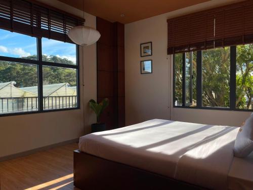 a bedroom with a large bed and large windows at Hôtel De Da Phu in Da Lat