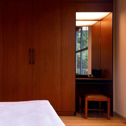 a bedroom with a bed and a window and a stool at Hôtel De Da Phu in Da Lat