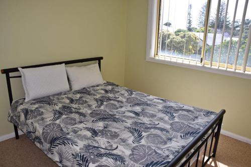 Un dormitorio con una cama con un edredón azul y blanco. en Village Centre 3 - Bring your own linen., en South West Rocks