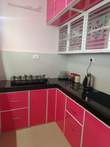 a kitchen with red cabinets and a stove in it at 2 BHK Furnished Flat - 200 m to Guruvayur Temple - For FAMILIES ONLY in Guruvāyūr