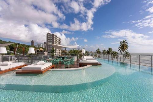 a hotel swimming pool with a view of the ocean at Flat beira mar de Cabo Branco em João Pessoa Setai YACHT in João Pessoa