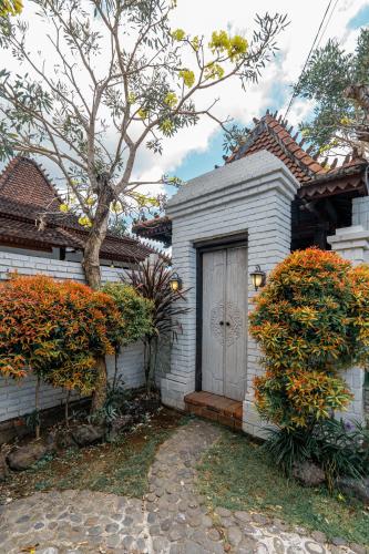 a white house with a door and some bushes at Sakya Villa Canggu By Bali Cabin in Canggu