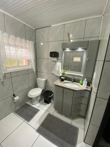 a bathroom with a toilet and a sink and a mirror at Sítio Nono Luiz in Benedito Novo