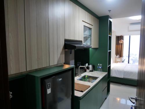 a kitchen with green walls and a sink and a bed at Meisterstadt Pollux Habibie in Batam Center