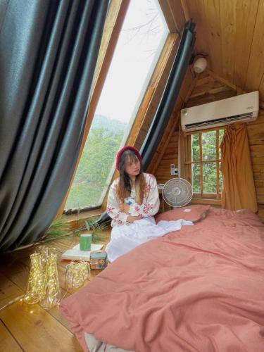 a woman sitting on a bed in a room at May Homestay Soc Son - Venuestay in Hanoi