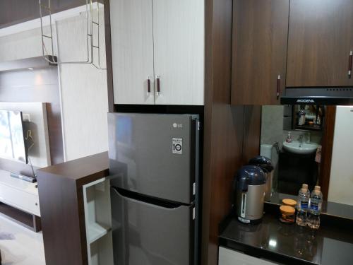 a kitchen with a stainless steel refrigerator and wooden cabinets at Meisterstadt Pollux Habibie in Batam Center