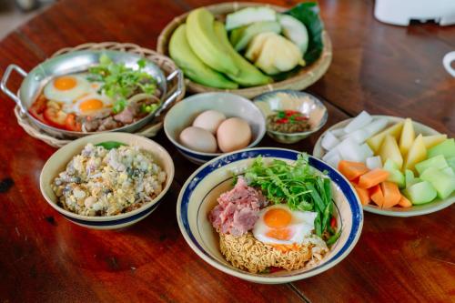 einen Holztisch mit Schalen mit Lebensmitteln und Gemüse in der Unterkunft Xóm Sình Homestay & Farmstay Buôn Ma Thuột ĐakLak in Ðat Lý (1)