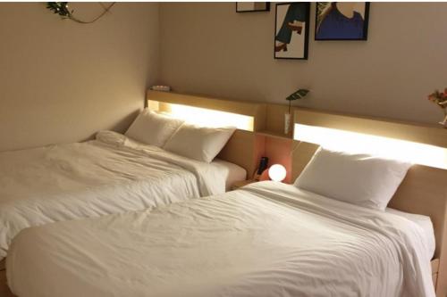 two beds in a hotel room with white sheets at The Stay Songdo Hotel in Incheon
