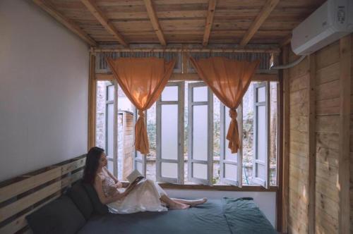 a woman sitting on a bed with a laptop in a window at May Homestay Soc Son - Venuestay in Hanoi