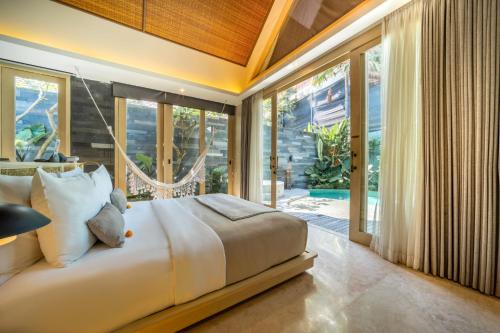 a bedroom with a large bed and large windows at Astera Luxury Resort & Spa Canggu by Ini Vie Hospitality in Canggu