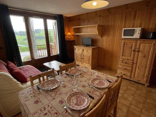 - une salle à manger avec une table et des assiettes dans l'établissement Appartement cosy 2 pièces - Proche pistes - Terrasse sud - 4 pers - FR-1-810-24, aux Saisies