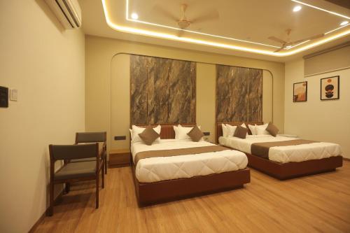 a hotel room with two beds and a chair at Hotel Raghavji in Rādhanpur