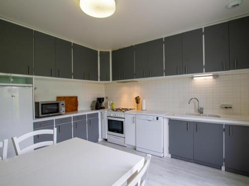 une cuisine avec des placards gris, une table blanche et un sidx de table dans l'établissement Maison Indépendante avec Grand Jardin, Cheminée, Wifi et Équipements de Loisirs à Agonac - FR-1-616-97, à Agonac