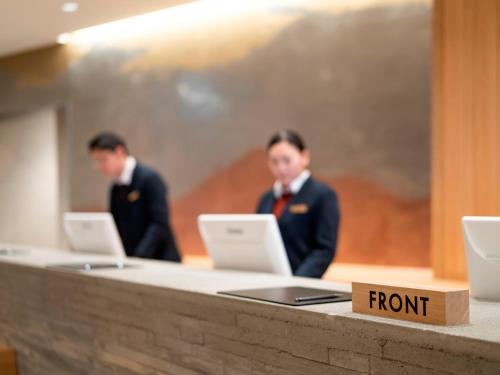two men in suits are working on their laptops at 層雲閣 in Kamikawa