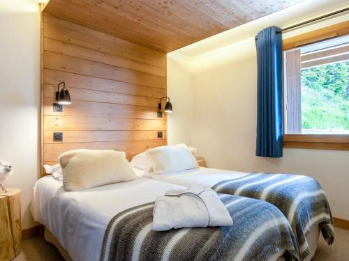 two beds in a bedroom with a wooden wall at Appartement de luxe aux Saisies avec SPA et parking pour 6 personnes - FR-1-810-16 in Les Saisies
