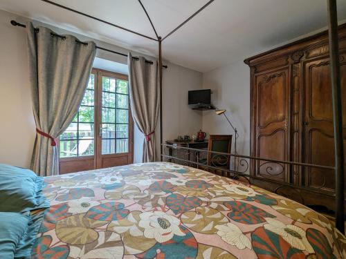 a bedroom with a bed with a floral bedspread at Ferme de charme avec piscine et tennis privés - FR-1-582-496 in Saint-Romain-Lachalm