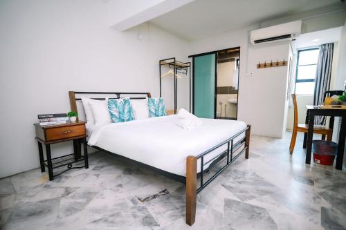 a bedroom with a large white bed and a table at Swing & Pillows - Seri Kembangan Selangor in Seri Kembangan