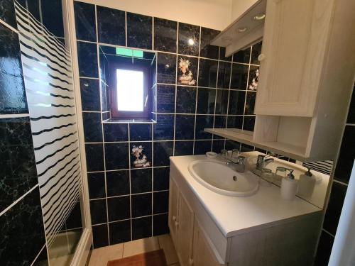 La salle de bains est pourvue de carrelage noir, d'un lavabo et d'une fenêtre. dans l'établissement Chambres d'hôtes au calme avec salle de jeux en Berry - FR-1-591-678, à Saulnay