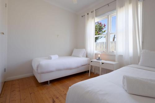 a white room with two beds and a window at Mary Grant in Port Fairy