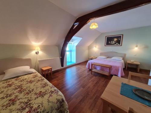 una camera da letto con due letti e un tavolo in una stanza di Ferme rénovée au calme - 4 chambres, petit-déjeuner inclu - FR-1-590-450 a Cravant