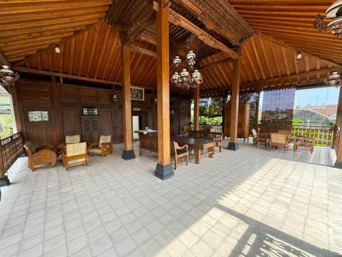 a large wooden pavilion with a table and chairs at Joglo Bandulan Homestay Jogja in Ngemplak