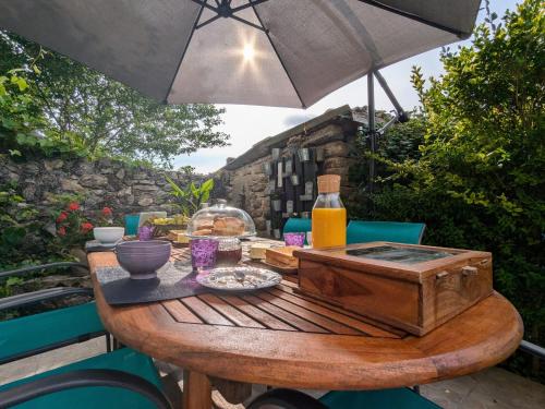 an outdoor table with an umbrella and a wooden table with a drink at Maison d'hôtes rénovée avec table d'hôte dans la campagne Altiligérienne - FR-1-582-522 in Saint-Victor-sur-Arlanc