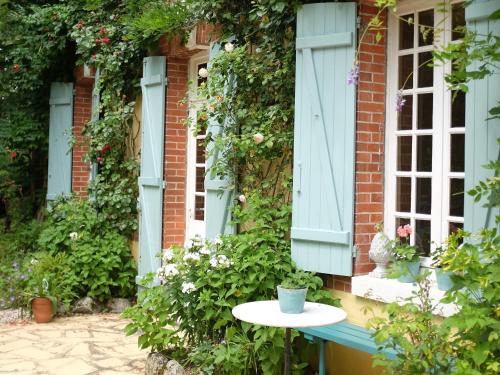 a table in front of a house with flowers at Chambre spacieuse, entrée privée, animaux admis, WiFi - FR-1-590-513 in Presnoy
