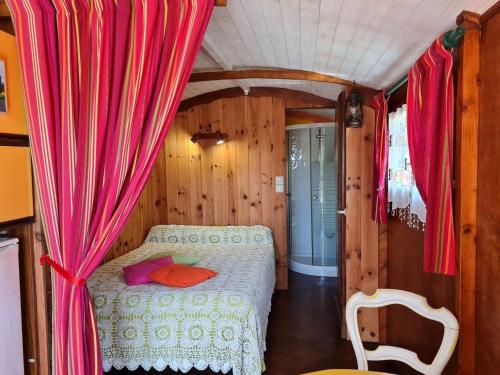 una camera con letto in una stanza con tende rosse di Roulotte Esméralda: Séjour insolite au cœur de la nature, climatisée, parking privé, prêt de vélos - FR-1-590-502 a Bonnée