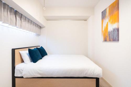a bedroom with a bed with white sheets and blue pillows at PL Park Lane Shirokane Takanawa in Tokyo