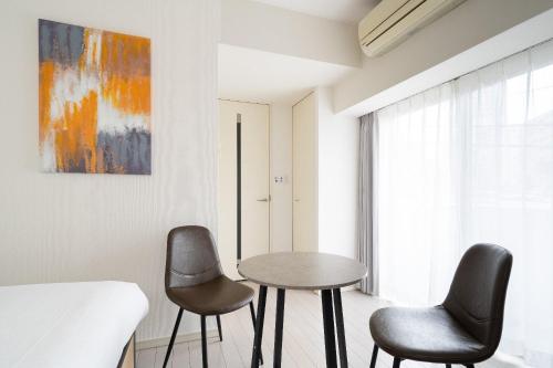 a room with two chairs and a table and a painting at PL Park Lane Shirokane Takanawa in Tokyo