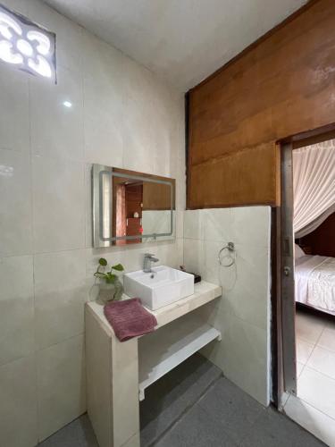 a bathroom with a sink and a mirror and a bed at Woody House in Bedugul
