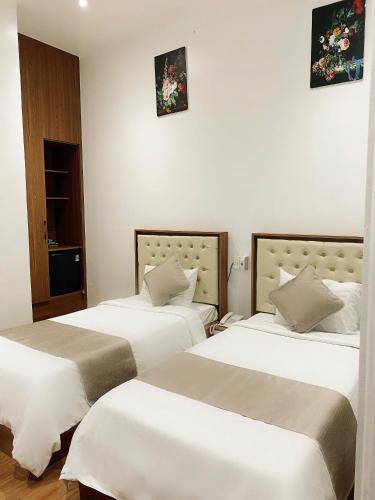 two beds in a room with white walls at Gaki Hotel in Hue