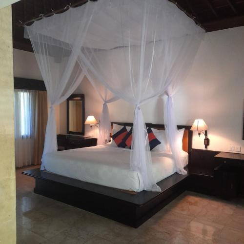 a bedroom with a large bed with a canopy at The Royal Beach Seminyak Bali in Seminyak