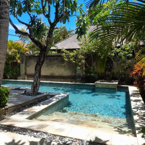 a swimming pool with a tree in the middle at The Royal Beach Seminyak Bali in Seminyak