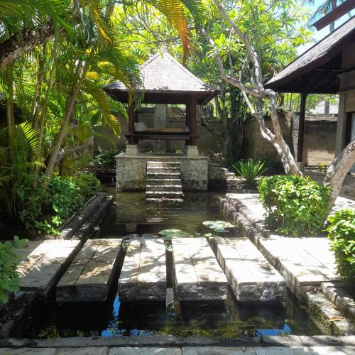 a garden with a pond in front of a building at The Royal Beach Seminyak Bali in Seminyak