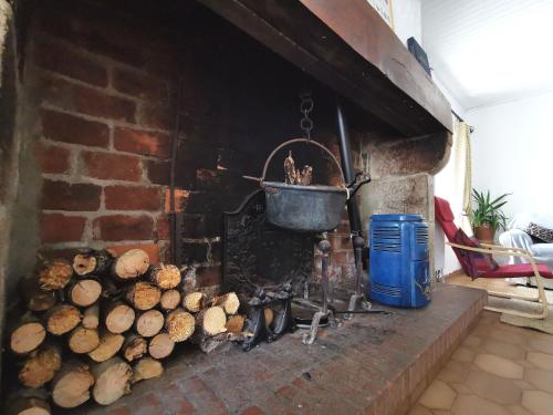 d'une cheminée en brique avec un pot et un tas de bûches. dans l'établissement Maison d'hôtes paisible avec petit-déjeuner près de la forêt - FR-1-582-509, à Sembadel