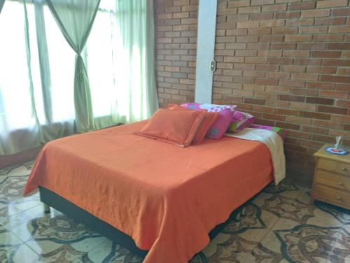 a bedroom with a bed with orange sheets and pillows at Cabaña condominio los sauces in Moniquirá