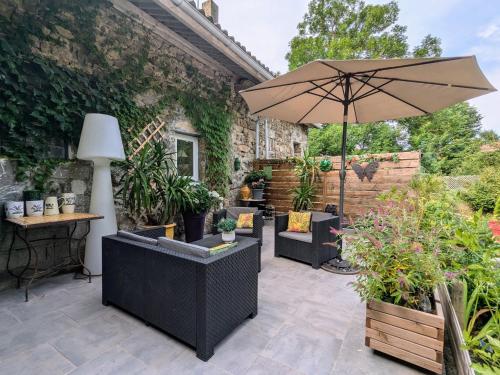 a patio with chairs and an umbrella and plants at Maison d'hôtes rénovée avec table d'hôte dans la campagne Altiligérienne - FR-1-582-522 in Saint-Victor-sur-Arlanc
