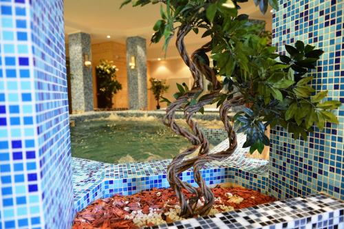 a bonsai tree in a bathroom with a swimming pool at Liza Aqua & Conference Hotel in Lajosmizse