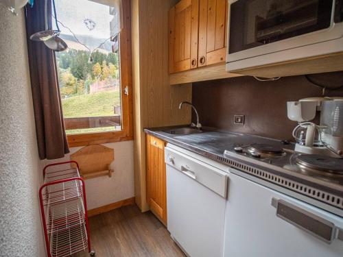 une cuisine avec un évier, une cuisinière et une fenêtre dans l'établissement Appartement 2P au pied des pistes, animaux admis - FR-1-356-523, à Valmorel