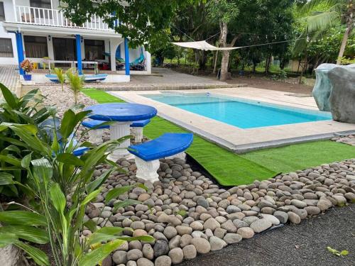 a swimming pool with two blue chairs next to a yard at Tivives kikala Lodge in Esparza