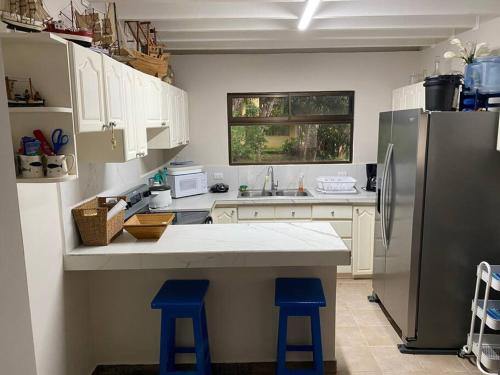 a kitchen with a refrigerator and two blue stools at Tivives kikala Lodge in Esparza