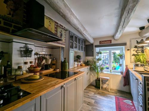 a large kitchen with a counter and a window at Maison d'hôtes rénovée avec table d'hôte dans la campagne Altiligérienne - FR-1-582-522 in Saint-Victor-sur-Arlanc