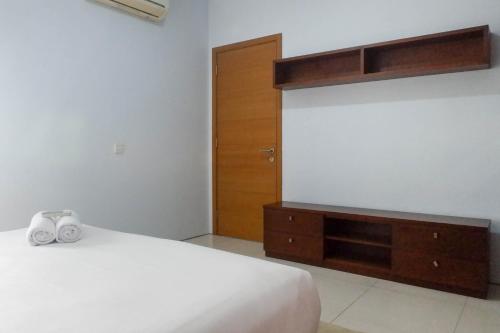 a bedroom with a bed and a dresser and a door at Modern 2BR Apartment at Aryaduta Residence Surabaya Connected to CITO Mall By Travelio in Surabaya